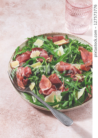 Fresh arugula salad with prosciutto and grated parmesan cheese, on a plate, homemade, no people, 127573776