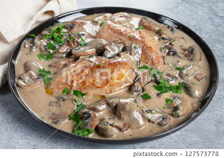 chicken in cream sauce with mushrooms, on a black plate, no people chicken in cream sauce with mushrooms, on a black plate, no people 127573778