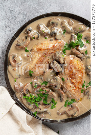 chicken in cream sauce with mushrooms, on a black plate, no people 127573779