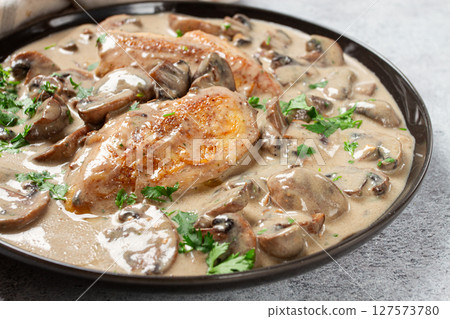 chicken in cream sauce with mushrooms, on a black plate, no people 127573780