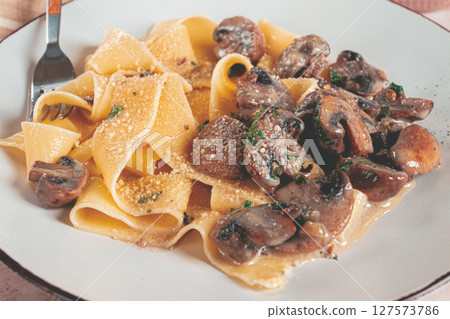 Delicious pappardelle pasta with mushrooms and cream served on a white plate Delicious pappardelle pasta with mushrooms and cream served on a white plate 127573786