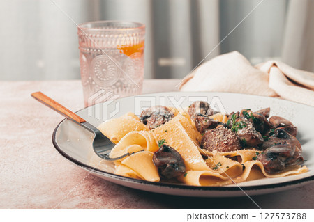 Delicious pappardelle pasta with mushrooms and cream served on a white plate Delicious pappardelle pasta with mushrooms and cream served on a white plate 127573788
