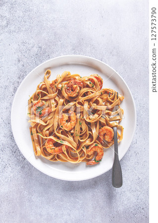 Fettuccine pasta with shrimp, spicy in soy sauce, on a grey plate with a fork, close-up, Fettuccine pasta with shrimp, spicy in soy sauce, on a grey plate with a fork, close-up, 127573790