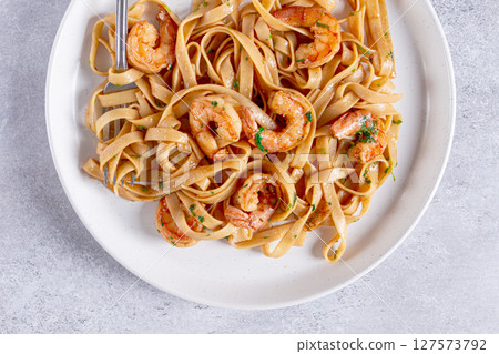 Fettuccine pasta with shrimp, spicy in soy sauce, on a grey plate with a fork, close-up, Fettuccine pasta with shrimp, spicy in soy sauce, on a grey plate with a fork, close-up, 127573792