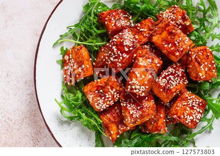 fried salmon slices, teriyaki with sesame seeds, with arugula salad, top view, 127573803