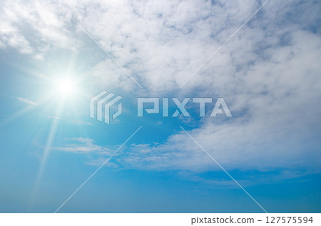 Bright sun and white clouds in clear blue sky 127575594