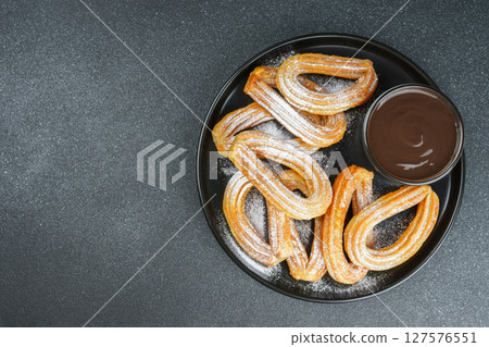 Traditional spanish dessert churros, fried dough pastry and chocolate sause on black background 127576551