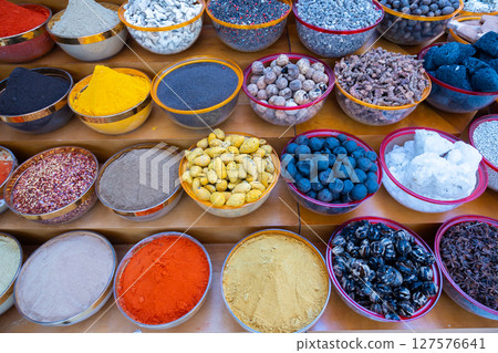 Traditional spices market. Pots and wooden tubs stand in row with colorful tea, spices, fruits, roots, flowers. Street bazaar. Dubai, UAE. Top view 127576641