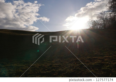 A hillside with a bright sun shining on it A hillside with a bright sun shining on it 127577174