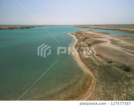 Shoreline of Kuimazar Reservoir curving around arid land in Uzbekistan's desert Shoreline of Kuimazar Reservoir curving around arid land in Uzbekistan's desert 127577387