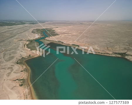 River delta, turquoise reservoir merging with dry steppe in central Uzbekistan River delta, turquoise reservoir merging with dry steppe in central Uzbekistan 127577389