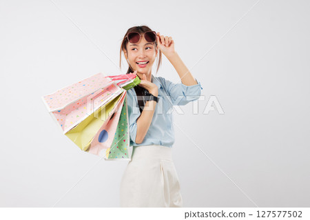Happy asian woman excited posing with shopping bag and sunglasses, Take off sunglasses, cheerful young lady holds a beautiful shopping bag, isolated studio white background 127577502
