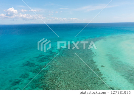 Tropical seascape with sea surface with corals and turquoise clear waters. Blue sky and clouds. Bantayan, Cebu, Philippines. 127581955