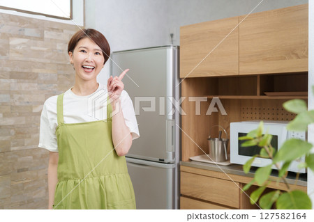 Woman pointing in kitchen 127582164