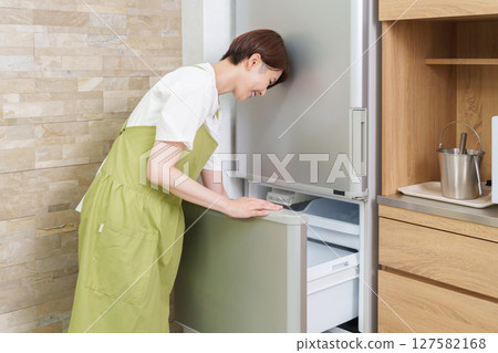A woman who opens a refrigerator 127582168