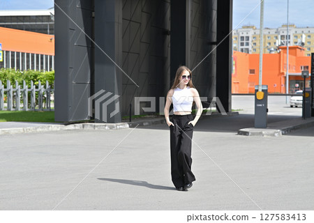 Woman walking near a retractable gate in front of a modern building. Woman walking near a retractable gate in front of a modern building. 127583413
