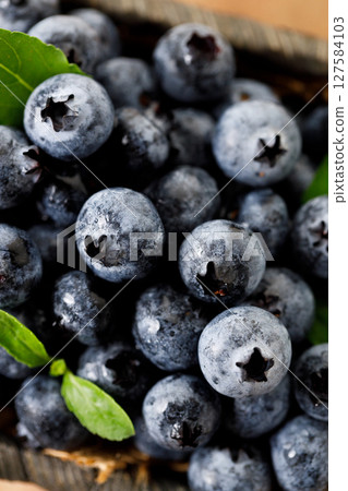 Ripe blueberries in wicker basket on wooden table. 127584103