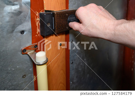 a man opens the lock on the front door of an apartment, a wooden door covered with metal a man opens the lock on the front door of an apartment, a wooden door covered with metal 127584179
