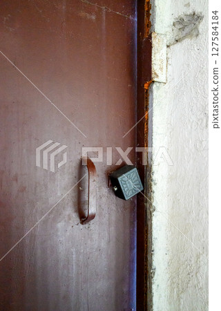 brown old iron door to house with black padlock 127584184