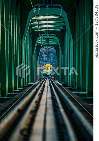 Pumpkin train running across the green iron bridge 127584335