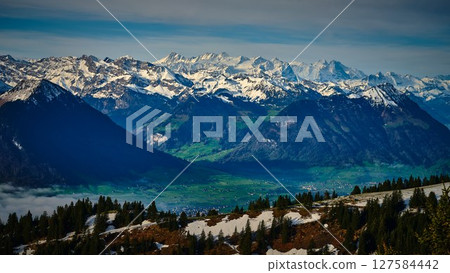 Majestic snow-capped mountains under a clear sky viewed from a high vantage point Majestic snow-capped mountains under a clear sky viewed from a high vantage point 127584442