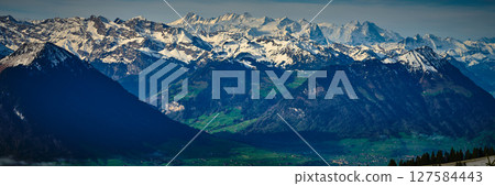 Stunning mountain range under a clear blue sky with snow-capped peaks and lush green valleys in Switzerland Stunning mountain range under a clear blue sky with snow-capped peaks and lush green valleys in Switzerland 127584443