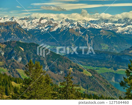 Snow-capped mountains rise majestically above lush valleys and serene lakes in stunning alpine landscape during summer Snow-capped mountains rise majestically above lush valleys and serene lakes in stunning alpine landscape during summer 127584460