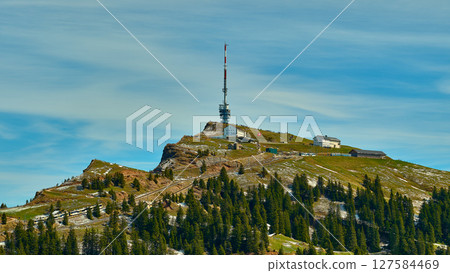 Tower and radio station on a mountain peak surrounded by lush greenery and a clear sky Tower and radio station on a mountain peak surrounded by lush greenery and a clear sky 127584469