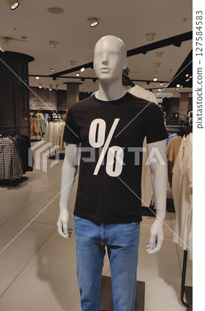 mannequin dressed in casual black t-shirt and blue jeans on display during sale in retail store. 127584583