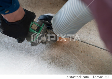 一名土木工程師在使用集塵器的同時，也用圓盤磨床切割混凝土。 127584982