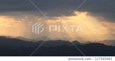 Sun hiding behind clouds and light shining through 127585061