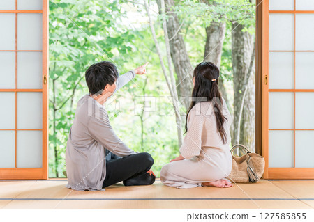 A couple staying at a hot spring inn and Japanese-style room on a domestic trip and looking at the garden view A couple staying at a hot spring inn and Japanese-style room on a domestic trip and looking at the garden view 127585855