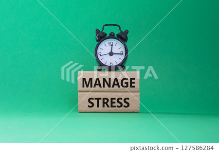 Manage stress symbol. Concept word Manage stress on wooden blocks. Beautiful green background with alarm clock. Business and Manage stress concept. Copy space 127586284
