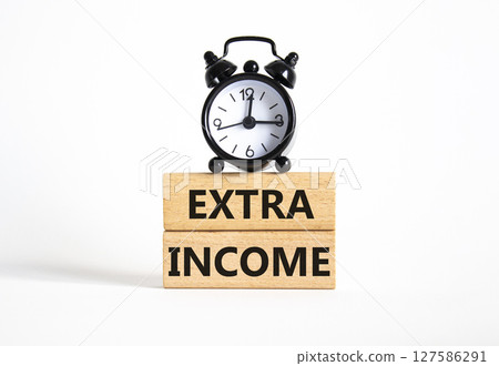 Extra Income symbol. Concept words Extra Income on wooden blocks. Beautiful white background with alarm clock. Business and Extra Income concept. Copy space. Extra Income symbol. Concept words Extra Income on wooden blocks. Beautiful white background with alarm clock. Business and Extra Income concept. Copy space. 127586291