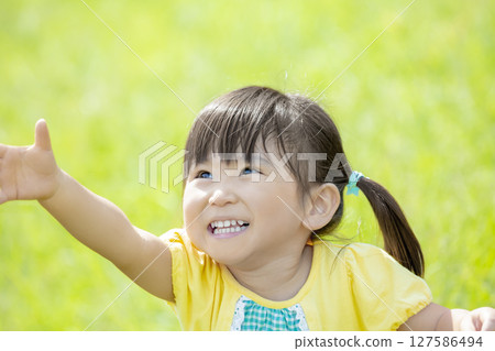 Girl playing in the grass in the park Girl playing in the grass in the park 127586494