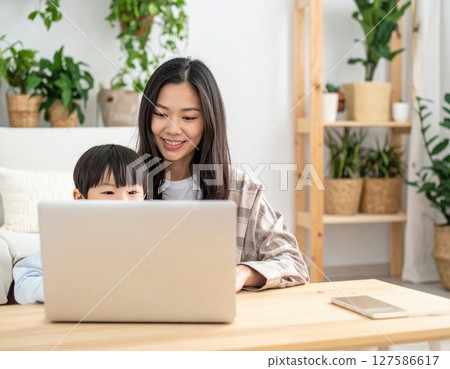 Parent and child learning to use a computer in the living room 127586617