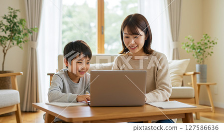 Parent and child learning to use a computer in the living room 127586636