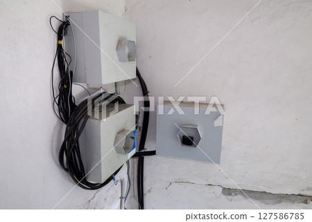 electrical equipment on the wall of the building, three distribution boards and electrical cables 127586785