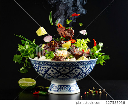 AI generated smoky thai sue rong hai grilled beef with fresh ingredients falling into ornate thai bowl juicy marinated steak spicy dipping sauce aromatic herbs 127587036