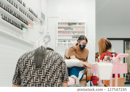 Nail technician manicure or pedicure at nail salon 127587285