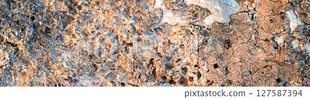 Horizontal close-up shot of rough volcanic stone with irregular surface, textured background. Horizontal close-up shot of rough volcanic stone with irregular surface, textured background. 127587394