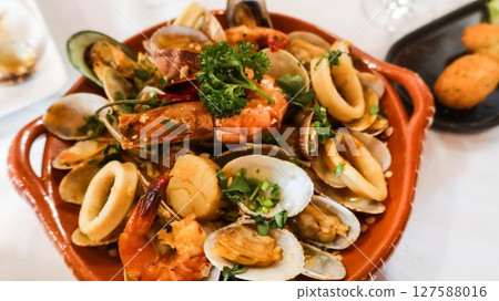 close up of Portuguese Arroz de Marisco, tomato brothy seafood rice on a red plate taken in a restaurant in Macau close up of Portuguese Arroz de Marisco, tomato brothy seafood rice on a red plate taken in a restaurant in Macau 127588016