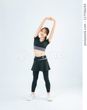 Full-body photo of a woman in sportswear stretching 127588264