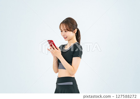A woman wearing sportswear looking at her smartphone A woman wearing sportswear looking at her smartphone 127588272