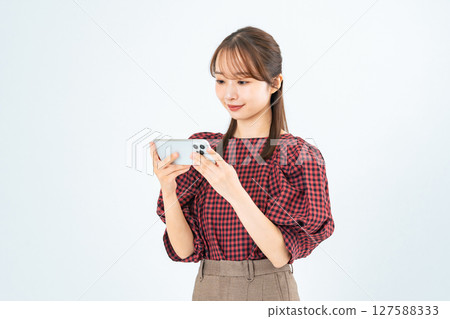 A woman in casual wear looking at her smartphone 127588333