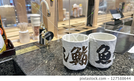 Hot water dispenser and teacups installed at a conveyor-belt sushi restaurant Hot water dispenser and teacups installed at a conveyor-belt sushi restaurant 127588644