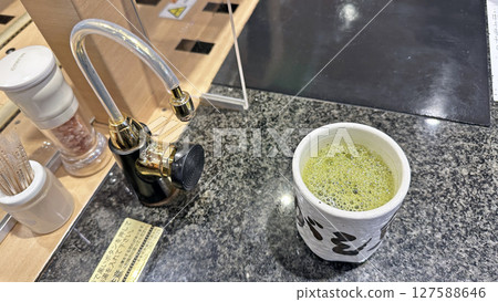 Hot water dispenser and teacups installed at a conveyor-belt sushi restaurant Hot water dispenser and teacups installed at a conveyor-belt sushi restaurant 127588646