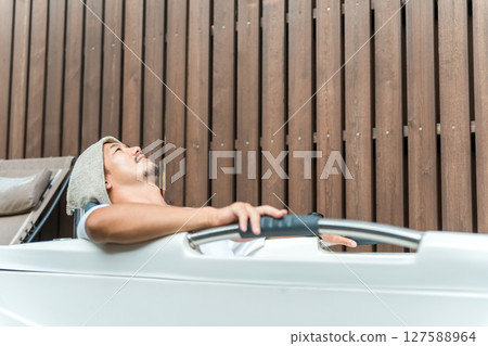 A man bathing in a cold water bath in a sauna at a campsite (open air bathing, forest bathing) A man bathing in a cold water bath in a sauna at a campsite (open air bathing, forest bathing) 127588964
