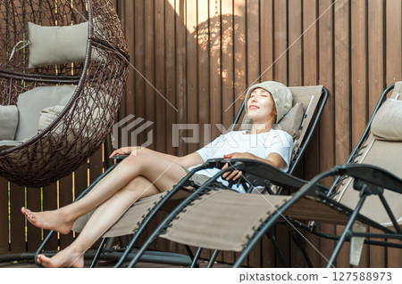 A woman sitting in a sauna chair in a sauna (spa, wellness, healing, refreshment, warming, detox) A woman sitting in a sauna chair in a sauna (spa, wellness, healing, refreshment, warming, detox) 127588973