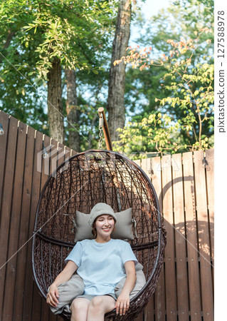 A woman sitting on a hanging chair in a sauna (spa, wellness, healing, refreshment, warming, detox) 127588978
